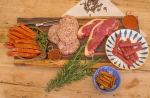The Smoker box: sausages, burger patties, steaks and chorizo on a wooden board